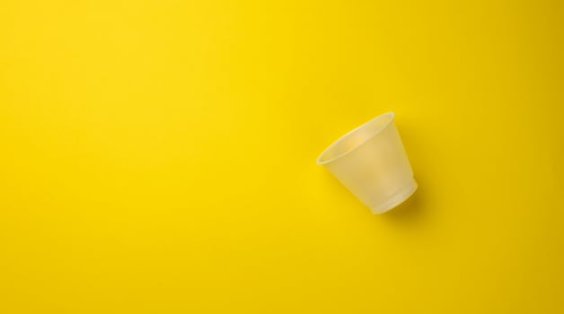 empty plastic cup on yellow background, top view photo