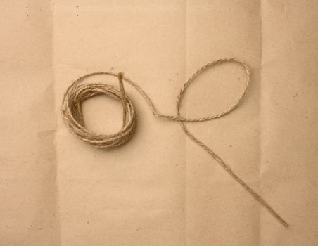 brown folded twine on a brown paper background, rope for household needs photo