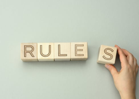 wooden blocks with the inscription rules on a gray background, hand holds a cube. The concept of setting the boundaries and conditions of the game photo