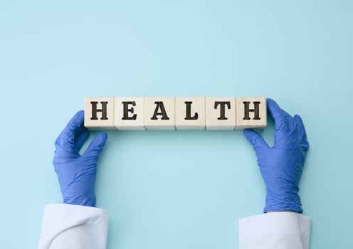 two female hands are holding wooden blocks with the inscription health on a blue background. Healthy lifestyle concept photo