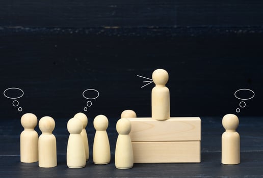 wooden figurines of men on a blue background. Public speaking concept, leadership and discussion. The team unites around an idea photo
