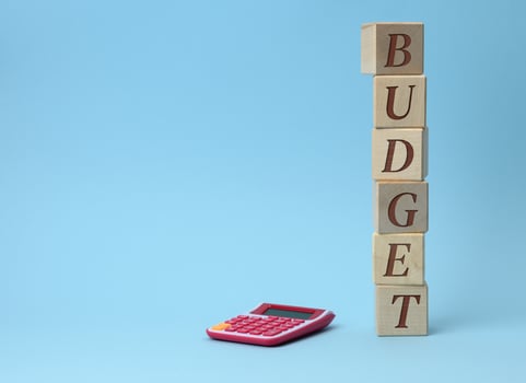 wooden cubes with the inscription budget and a pink calculator on a blue background photo