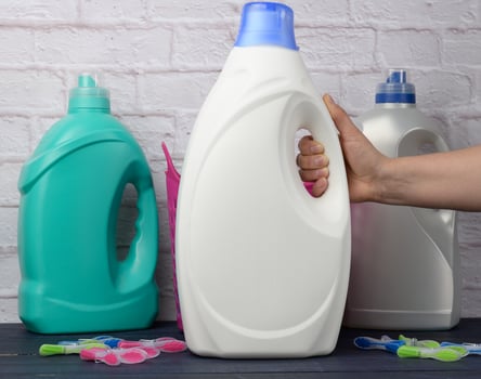 woman's hand holding a large white plastic bottle with detergent for washing clothes photo