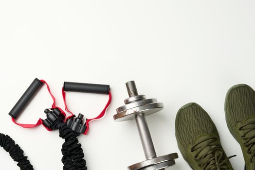 pair of green textile sneakers and a metal dumbbell on a white background, top view. Shoes for sports photo
