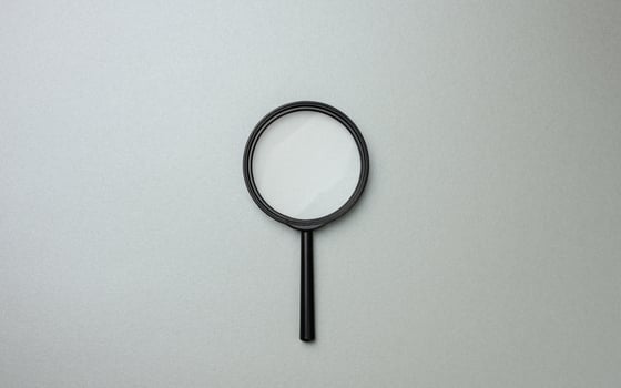 black magnifier on a gray background and question marks. The concept of uncertainty and the search for solutions photo