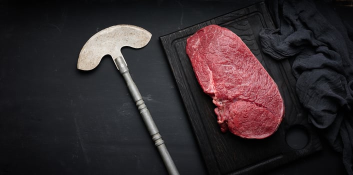 Raw beef tenderloin lies on a cutting board on a black table, top view photo