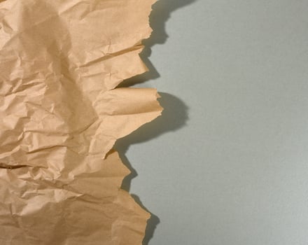 mint brown piece of paper with torn edges and shadow on gray background. Abstract creative backdrop for designer photo