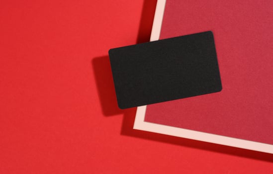 blank black rectangular business card lies on a modern red background with red sheets of paper with a shadow. Business template photo