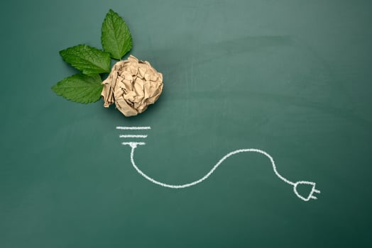 crumpled sheet of brown paper and a green leaf on a green background, shape of a light bulb. photo