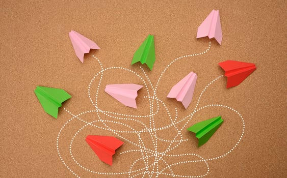 group of multicolored paper planes with long tangled paths on a brown background. photo