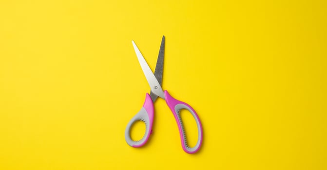 metal scissors with pink plastic handle on a yellow background photo