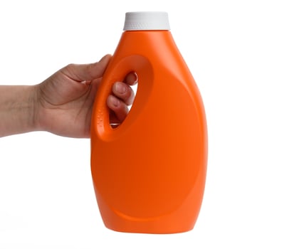 female hand holding orange plastic bottle for liquid laundry detergent photo