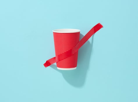red cardboard cup glued with red sticky tape to the blue background photo