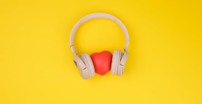 red heart and beige wireless headphones on a yellow background photo