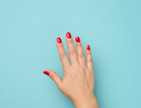 female hand with red manicure raised up on a blue background photo