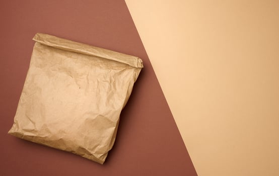 full brown paper disposable food bag on a brown background, concept of delivery and ordering photo