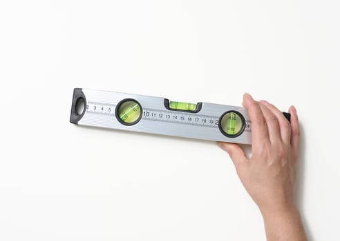 female hands holds a gray metallic building level on a white background. Measuring instrument photo