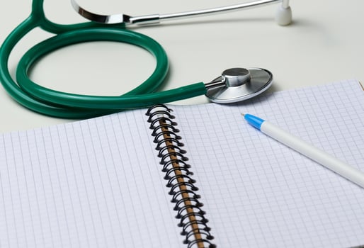 open blank notebook with pen and stethoscope, white table photo