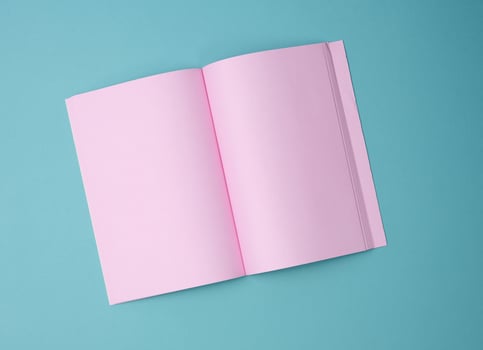 open notebook with blank pink sheets on blue background, top view photo