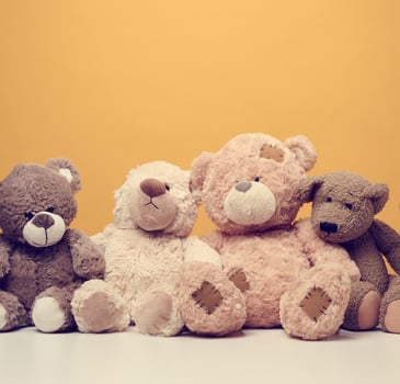 group of cute brown teddy bears sit on yellow background, childrens toy photo