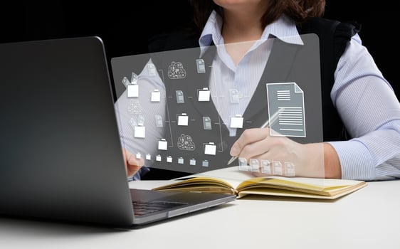 Woman sits at a table and works with a laptop. Document management system DMS photo