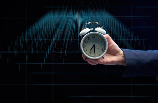 hand of a businessman holds a round alarm clock on the background of charts. The concept of time is money. photo