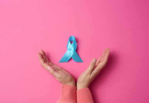 woman hands holding light blue ribbon awareness on a pink background. Men's health and prostate cancer awareness campaign concept. photo