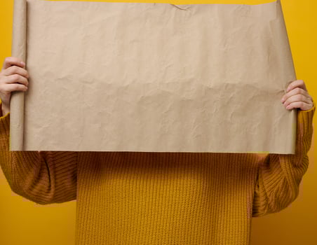 woman holding blank brown parcel of brown kraft paper. Place for an inscription, advertisement, information photo