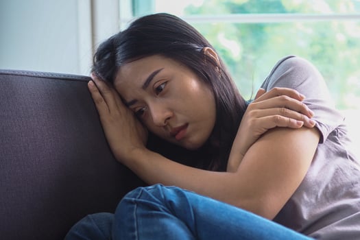 A sad girl sitting on the sofa worrying and worried. photo