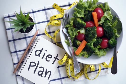 Healthy eating concept. Vegetable salad, food control notebook and tape measure photo