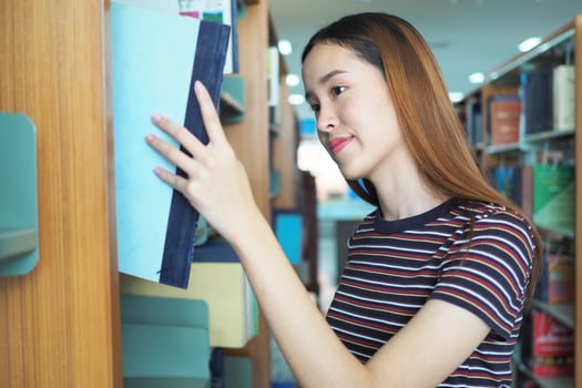 High school or college students are choosing books on shelves in the library. photo