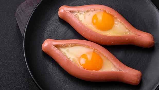 Composite concept of fried eggs inside a cut sausage with spices photo