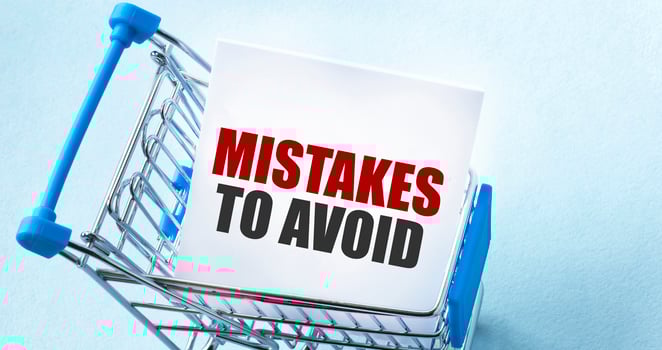 Shopping cart and text Mistakes To Avoid on white paper note list. Shopping list concept on blue background. photo