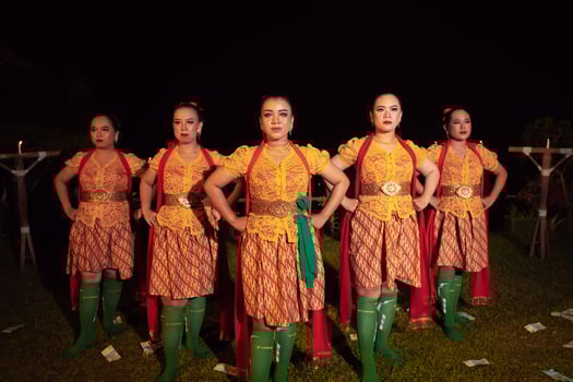 Balinese dancers standing together with red scarf and orange costumes on the stage after performing the traditional dance photo
