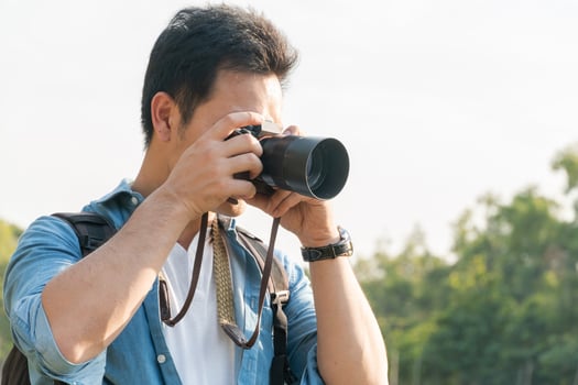 Asian man photographer shooting landscape picture with camera photo