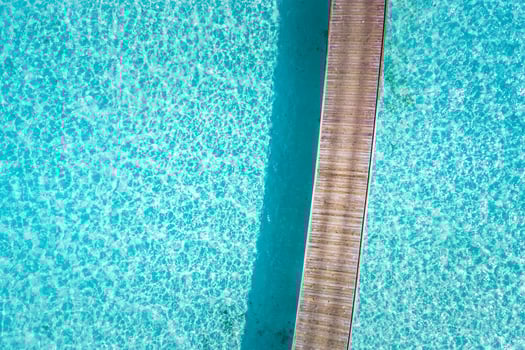 Aerial top view tropical island bay. Wooden pier bridge with blue lagoon in Maldives island, Beautiful tropical Maldives resort hotel. photo