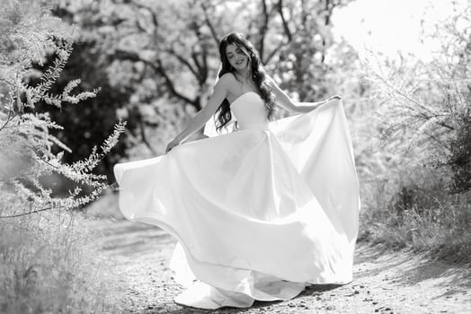 a young girl bride in a white dress is spinning on a path photo