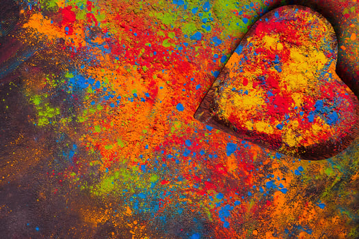 Organic multicolored bright Holi colors in heart shaped wooden plate on dark background for Holi festival celebration, copy space. photo