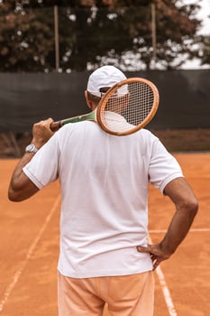 a retired tennis player dressed in sportswear posing with his back to the camera on a clay tennis court photo