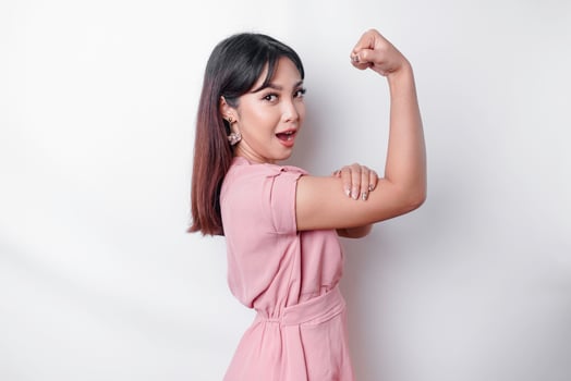 Excited Asian woman wearing a pink blouse showing strong gesture by lifting her arms and muscles smiling proudly photo