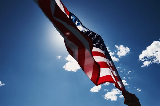 Waving usa flag in hand against blue sky photo