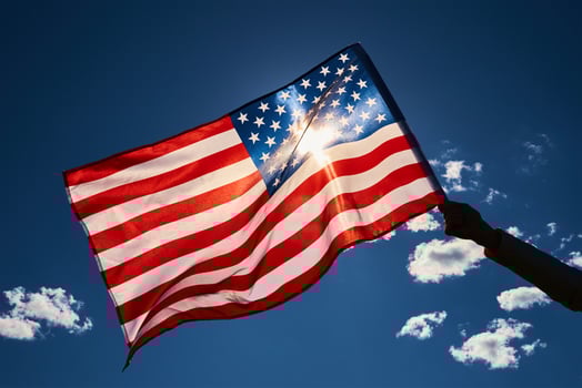 Waving usa flag in hand against blue sky. photo