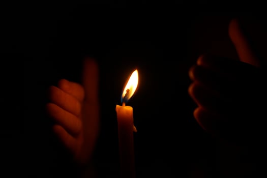 Human hands protect candlelight at night that illuminates things. photo