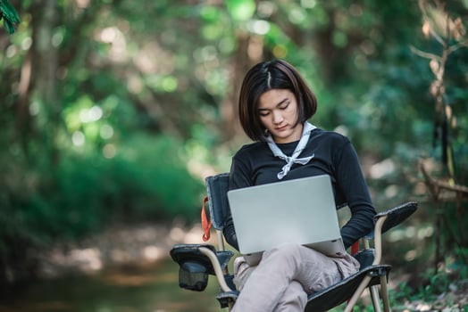 Young woman use laptop while camping in forest photo