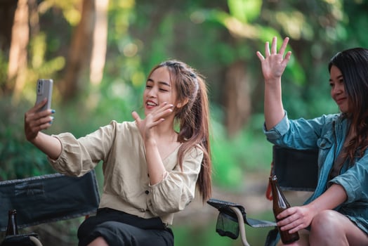 Young women drink beers and use smartphone take photo