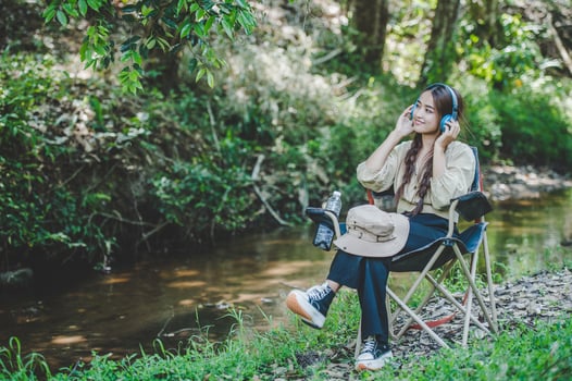 Young asian woman sitting on chair listening music from headphone photo