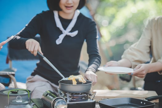 Young woman cooking with egg while camping with girl friend photo