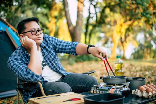 Portrait of Asian traveler man glasses frying a tasty fried egg photo