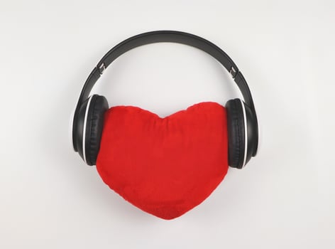 flat lay of red heart pillow coverd with headphones on white  background. Love songs or podcast concept. photo