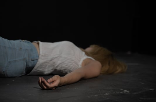 Female victim of violent crime lies on floor in dark room photo